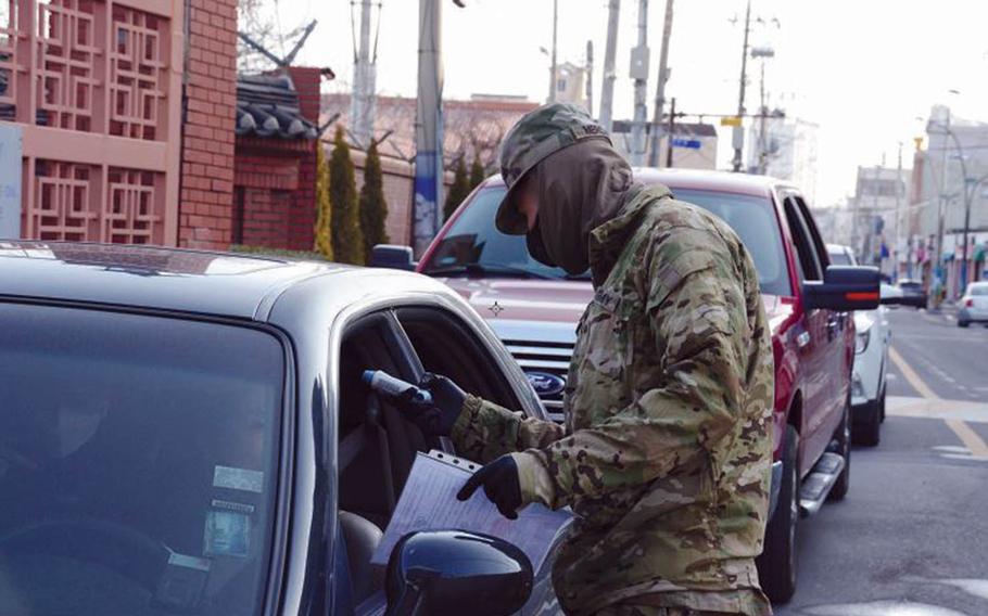 A soldier with the 25th Transportation Battalion checks temperatures before allowing people to enter Camp Walker in Daegu, South Korea, Feb. 22, 2020.