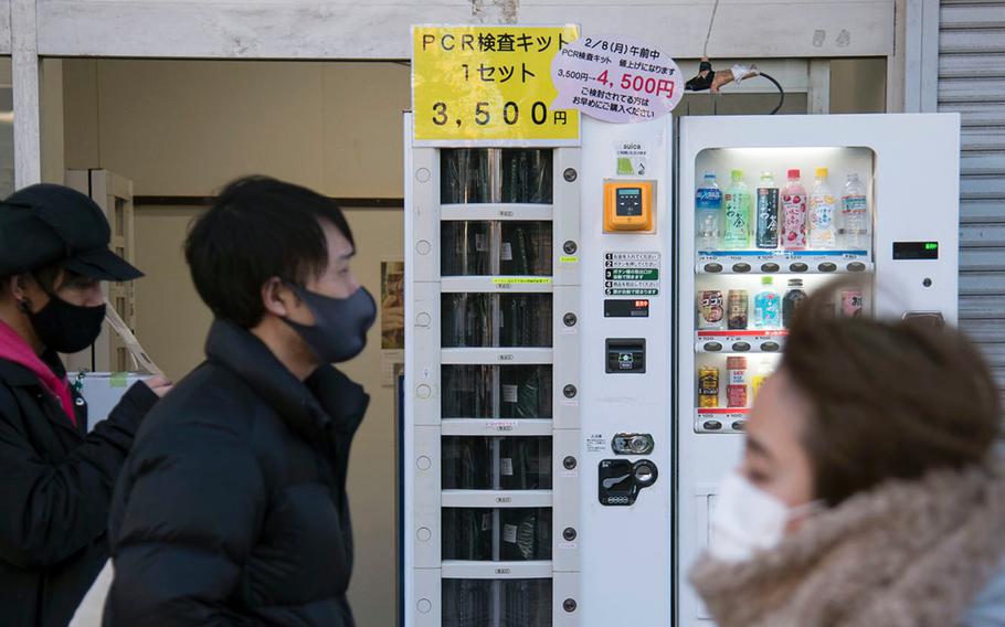 People walk past a vending machine selling polymerase chain reaction kits, which test for the coronavirus, near Ofuna Station in Kanagawa prefecture, Japan, Thursday, Feb. 4, 2021.