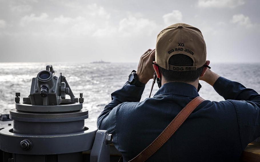 Cmdr. Joseph Gunta, executive officer of USS John S. McCain, observes a surface contact as the the guided-missile destroyer steams near the Paracel Islands in the South China Sea, Friday, Feb. 5, 2021.