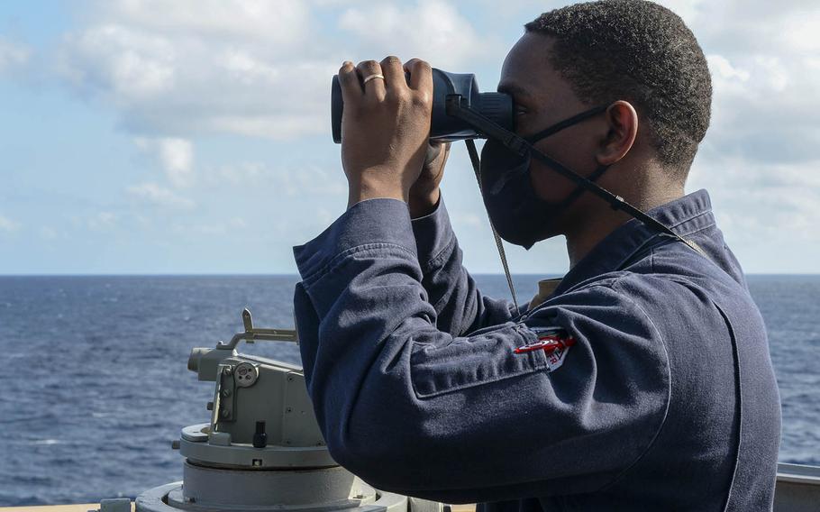 Ensign Ryan Simpson, of Baltimore, watches from the bridge wing of the USS Russell as the guided-missile destroyer steams through the South China Sea, Wednesday, Feb. 17, 2021.