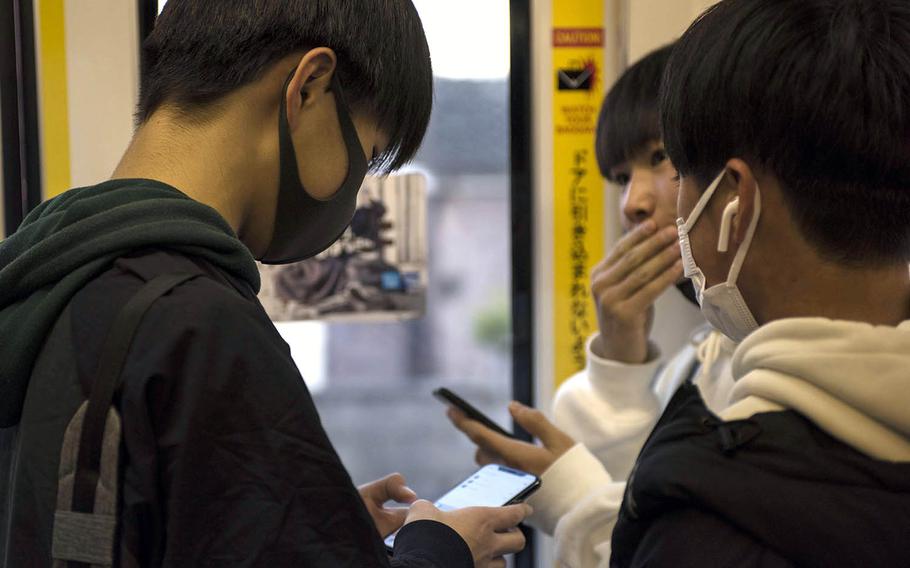 Young men wear masks as protection against the coronavirus while riding a train this month in western Tokyo. 