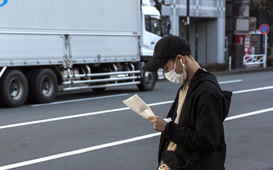 A  man wearing a mask as protection against the coronavirus pauses on a street in Hachioji, Japan, Feb. 2, 2021.