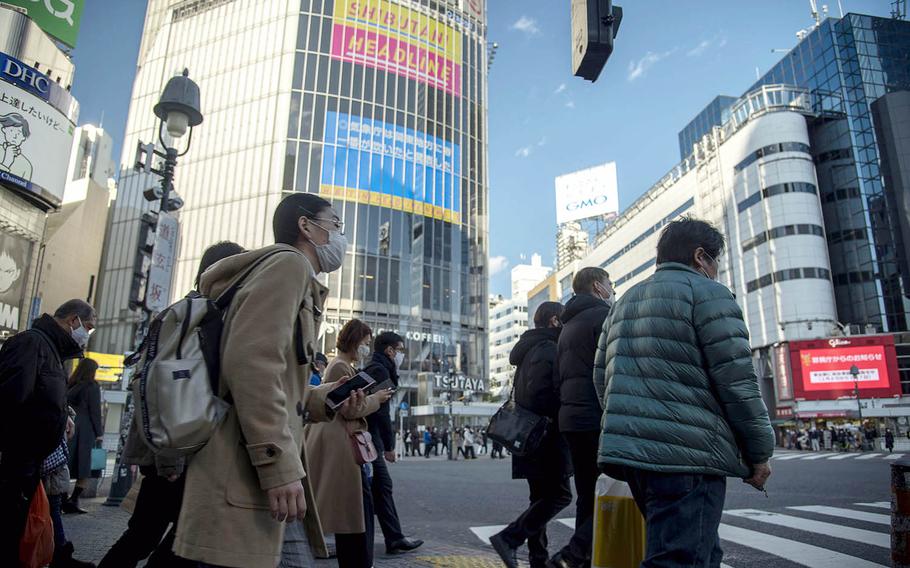 Masked pedestrians prepare to cross the busy Shibuya Scramble intersection in central Tokyo, Feb. 4, 2021. 