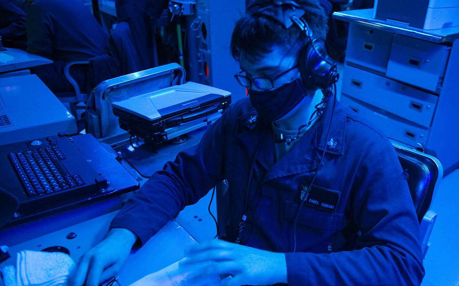 Petty Officer 2nd Class Pavel Gorski, a fire controlman from St. Petersburg, Fla., writes in a watch log as the guided-missile destroyer USS Curtis Wilbur passes through the Taiwan Strait, Tuesday, Feb. 23, 2021.