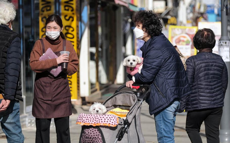 People in masks go out for a walk in Pyeongtaek, South Korea, Tuesday, March 2, 2021.