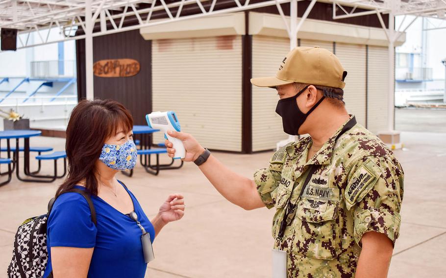 Petty Officer 1st Class Arvin Quiambao screens a colleague for coronavirus symptoms at Yokosuka Naval Base, Japan, Sept. 1, 2020.