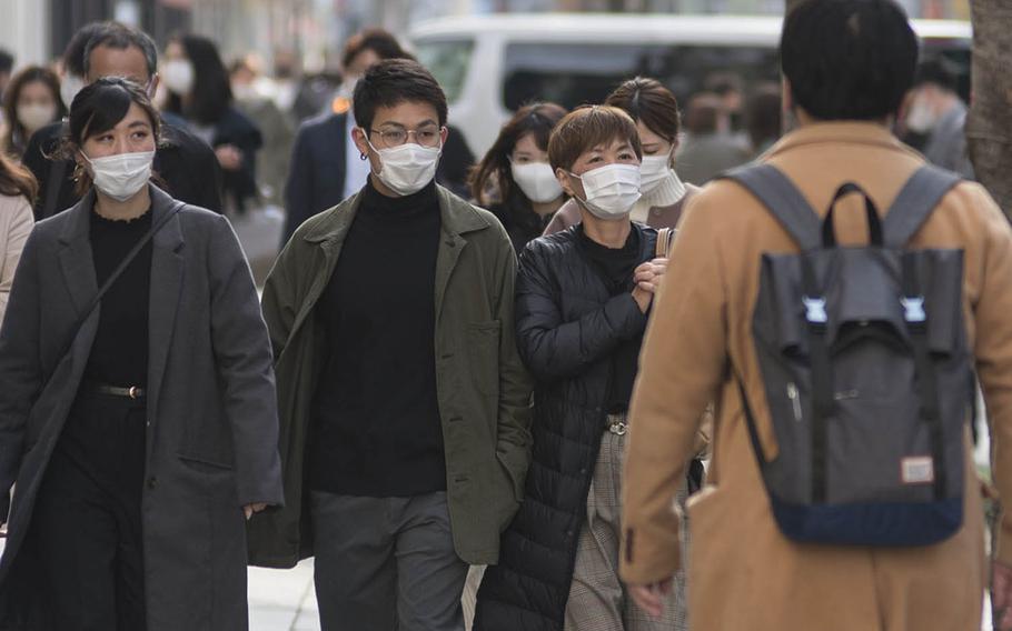Pedestrians in Ginza, a shopping district in central Tokyo, wear masks as protection against the coronavirus, Tuesday, March 9, 2021. 