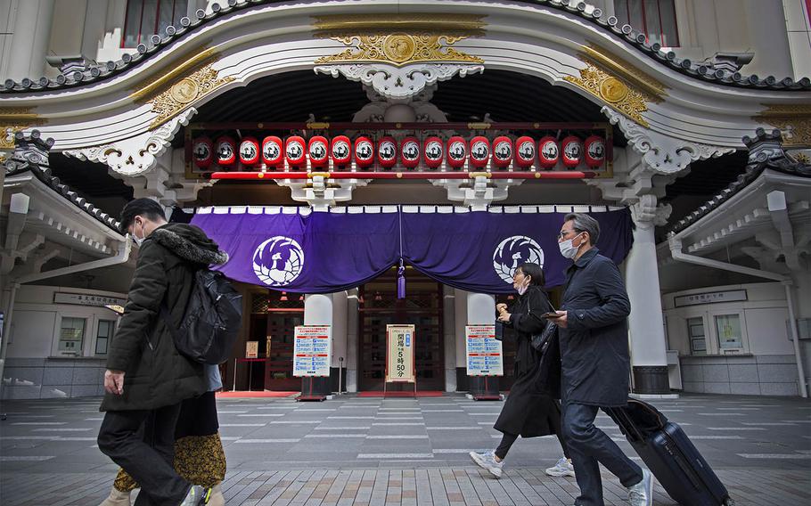 People wear masks as they stroll past the Kabukiza Theatre in Ginza, Tokyo, March 9, 2021. 