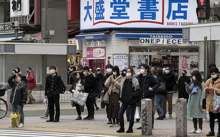 One woman is the exception among a group of pedestrians in central Tokyo wearing masks as protection against the coronavirus, Feb. 26, 2021.
