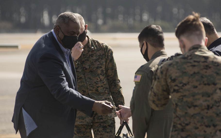 Defense Secretary Lloyd Austin hands a challenge coin to an airman at Yokota Air Base, Japan, Wednesday, March 17, 2021. 