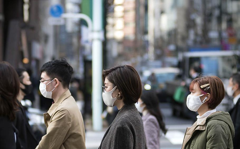 Pedestrians wear masks to guard against the coronavirus in the Ginza district of central Tokyo, March 9, 2021. 