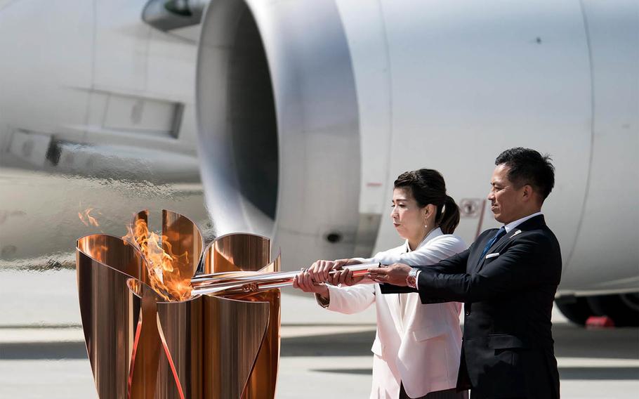 Japanese gold-medalists Tadahiro Nomura, right, and Saori Yoshida light an Olympic cauldron with the flame brought from Greece to Matsushima Air Base in Miyagi prefecture, Japan, Friday, March 19, 2021.