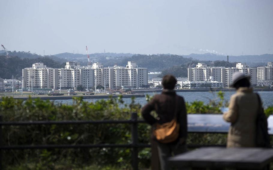 People visiting an observation point check out housing towers and other buildings at Yokosuka Naval Base, Japan, March 19, 2021. 