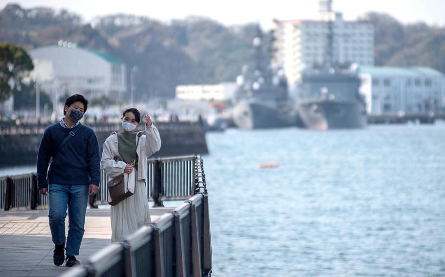 Two people walking along the Yokosuka, Japan, waterfront wore masks as prevention against the coronvirus on March 19, 2021.