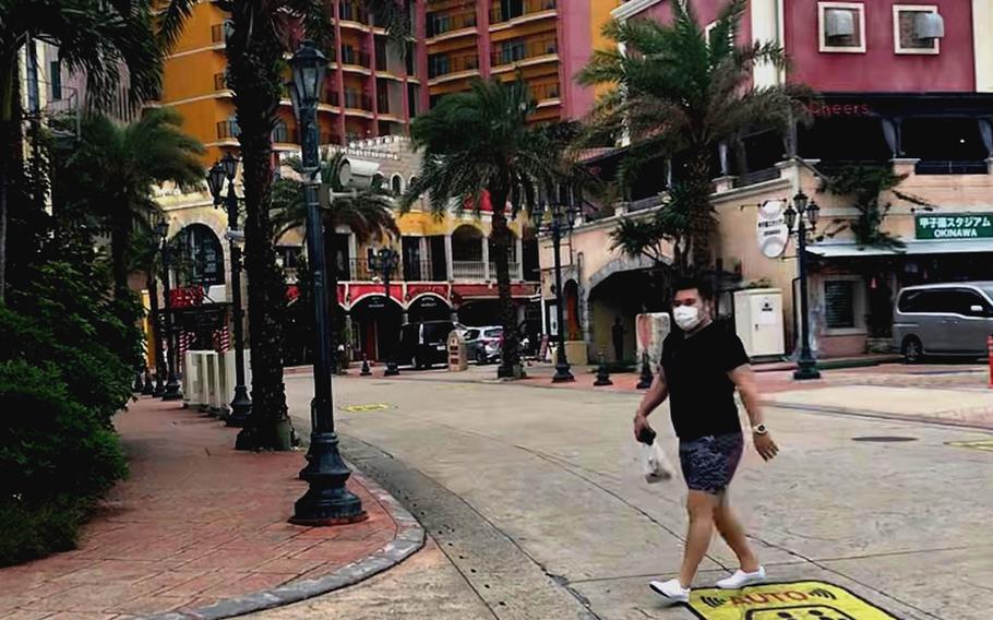 A masked pedestrian strolls through American Village, a popular tourist spot on Okinawa, Tuesday, April 6, 2021.