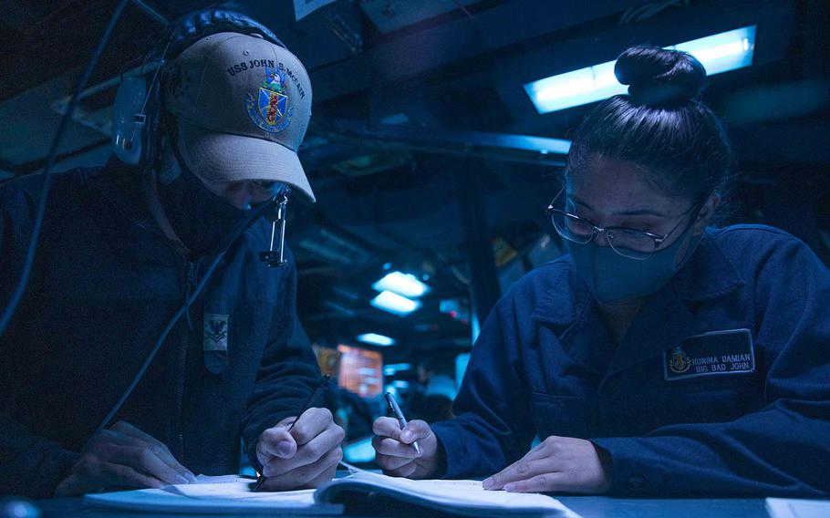 Petty Officer 2nd Class Tyler Manning, of Orlando, Fla., and Seaman Korina Damian, of Lake Havasu, Ariz., stand watch in the combat information center as the USS John S. McCain sails through the Taiwan Strait, Wednesday, April 7, 2021. 