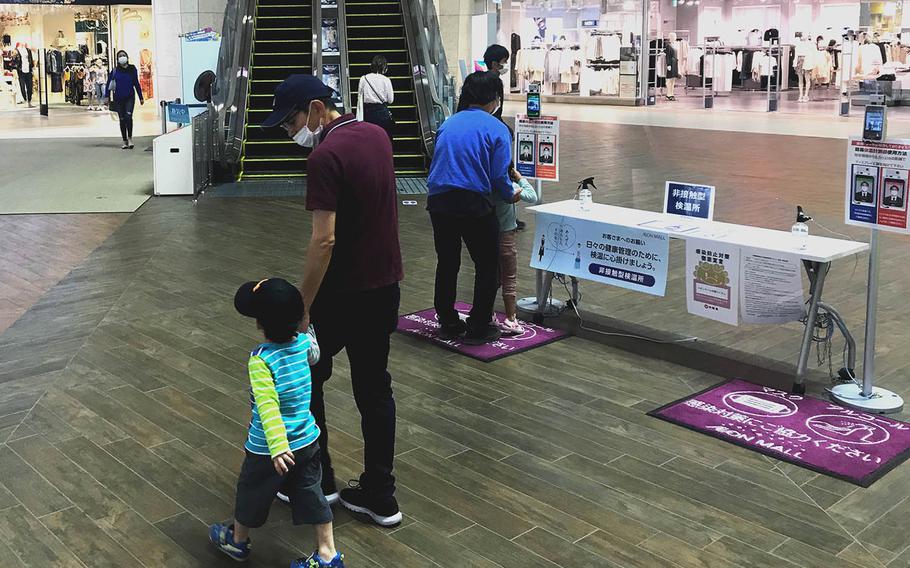 A table for hand sanitizer and thermometers occupies a central spot inside an Okinawa mall, Thursday, April 8, 2021. 