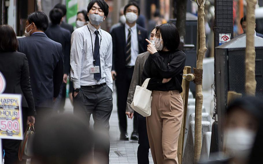 People wearing masks to guard against the coronavirus stroll through Tokyo on April 13, 2021. 