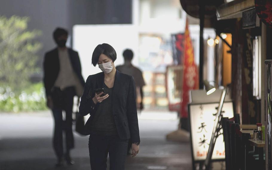 A woman in a protective mask walks through a park in central Tokyo on April 13, 2021. 