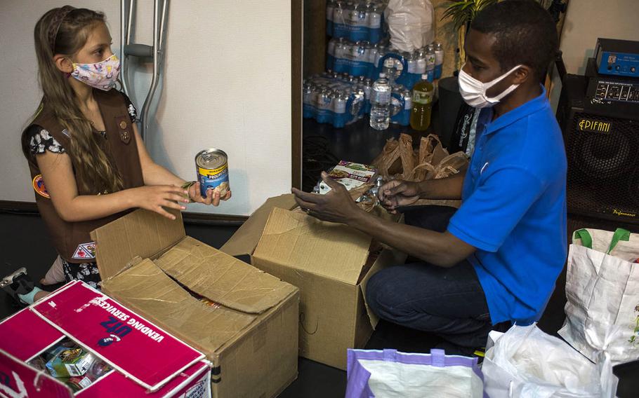 Girl Scout Eleanor Pierson, 9, of Yokota Air Base, Japan, helps Marcel Gadsden, pastor of the Japan Kingdom Builders Church in Fussa, sort hundreds of nonperishable food items she collected for the homeless, April 20, 2021. 