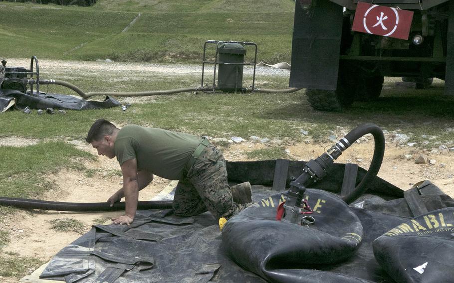 A Marine from the 9th Engineer Support Battalion checks to make sure fuel is running to a 500-pound bladder during a combat readiness exercise for the 1st Marine Aircraft Wing at Kin Blue Beach, Okinawa, April 20, 2021.