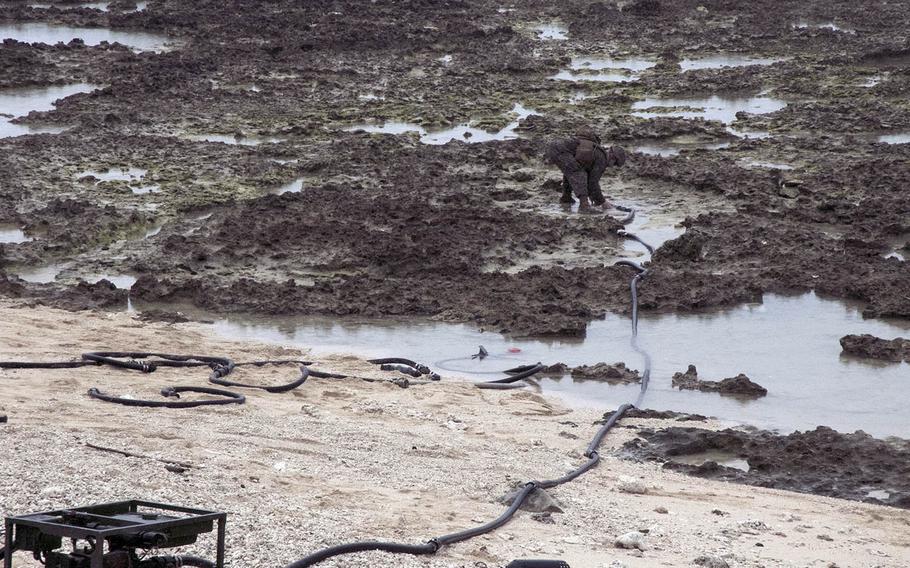 A member of Marine Wing Support Squadron 172 sucks up seawater that will be purified during an exercise on Ie Shima, Okinawa, April 16, 2021.