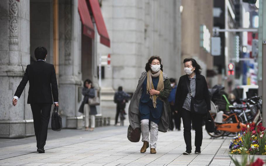 Pedestrians in central Tokyo wear face masks to prevent the spread of the coronavirus, April 6, 2021.  