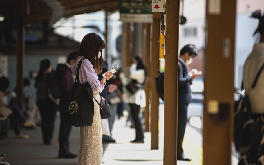 Travelers in coronavirus masks wait for their trains at Kamakura Station in Kanagawa prefecture, Japan, April 27, 2021.