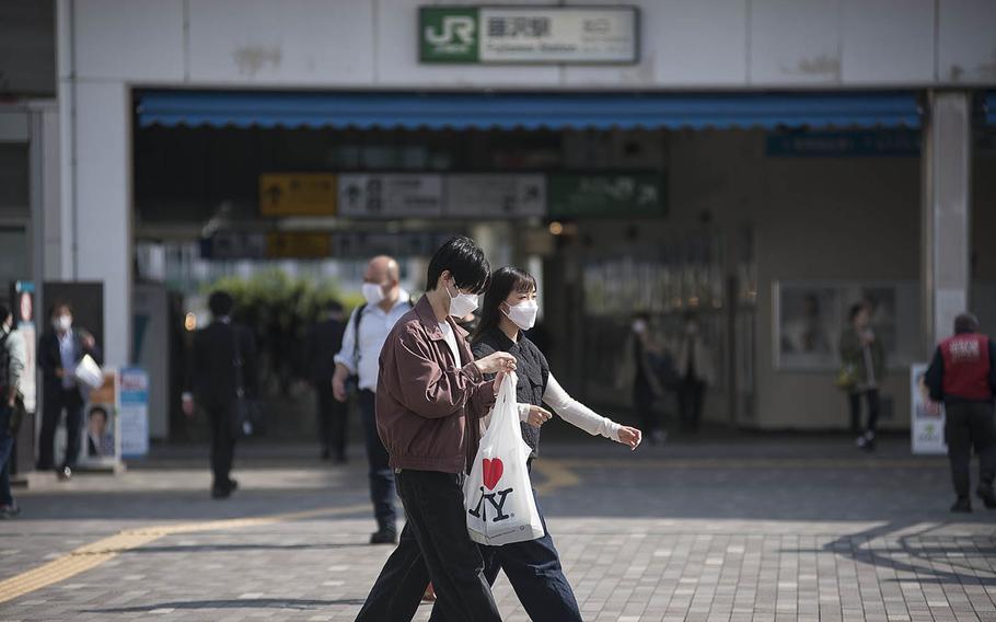 Pedestrians in coronavirus masks walk past Fujisawa Station in Kanagawa prefecture, Japan, April 27, 2021.  