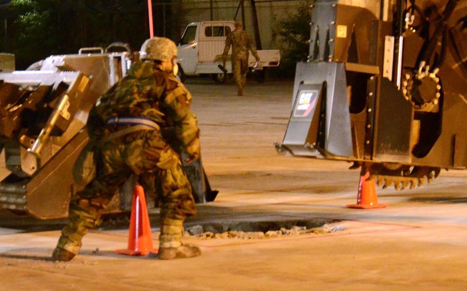 An airman from the 374th Civil Engineer Squadron guides a concrete cutter while training to rapidly repair damaged runways during an exercise at Yokota Air Base, Japan, Wednesday, May 5, 2021. 