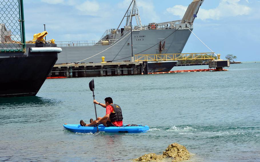 Jonah Lee, an 18-year-old high school senior in Hawaii, kayaks past Navy ships at Joint Base Pearl Harbor-Hickam, Hawaii, April 23, 2021.