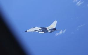 A jet flies over a sea.