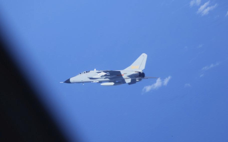A jet flies over a sea.