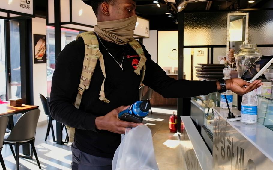 A U.S. soldier uses hand sanitizer after receiving his take-out order from a kebab restaurant outside Camp Humphreys, South Korea, Friday, March 1, 2020.
