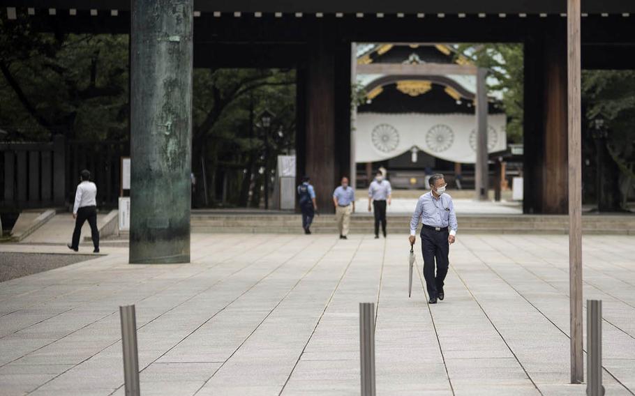 People wear masks as they stroll the grounds of Yasukuni Shrine in central Tokyo, Monday, July 27, 2020.