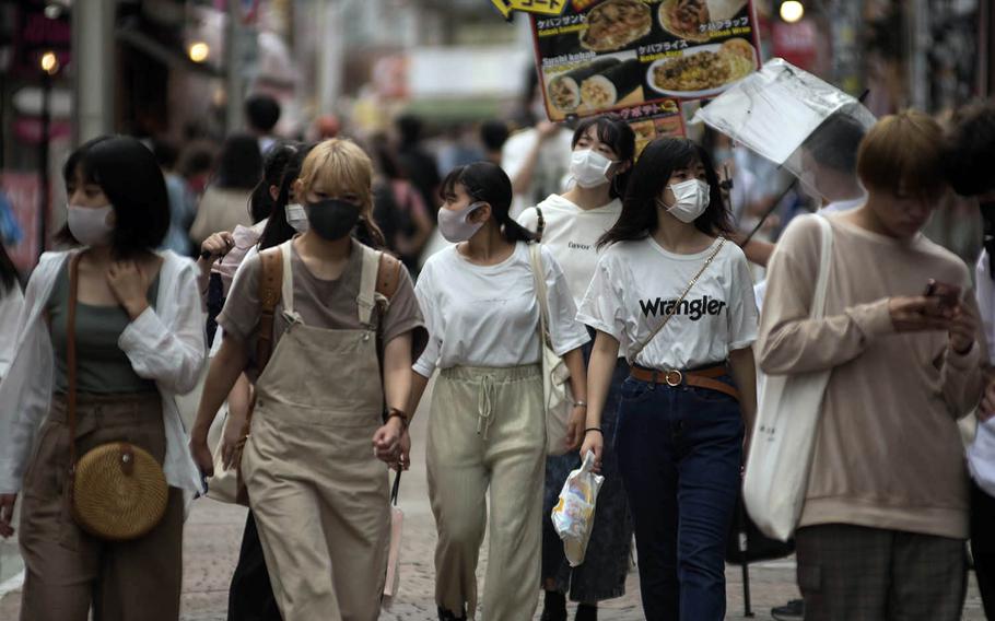 People wear masks as they stroll Takeshita Street, a pedestrian area lined with fashion boutiques, cafes and eateries in Harajuku, Tokyo, Monday, July 27, 2020.