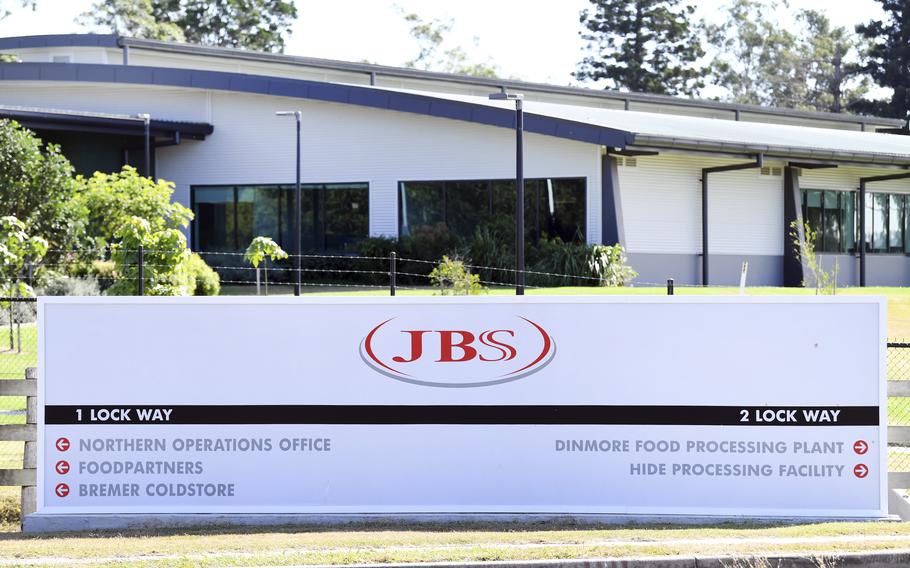 In this May 12, 2020, photo, the company logo sign sits at the entrance to the JBS Australia's Dinmore meatworks facility, west of Brisbane. 