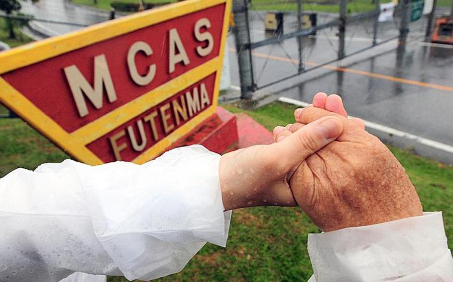 Thousands of anti-base protesters held hands around the eight-mile fence surrounding Marine Corps Air Station Futenma, symbolically closing the base, during a demonstration last month.