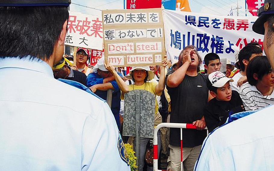 Demonstrators gather outside the Futenma Elementary School No. 2, chanting anti-military base slogans, while inside some protesters shouted 'Shame! Shame!' to then-Prime Minister Yukio Hatoyama during a town hall meeting last month in which he declared that U.S. Marine units would not be transferred off Okinawa.
