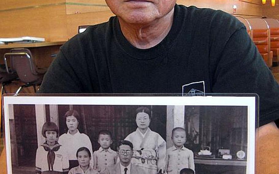 Seiei Kiyuna, 77, who survived the Battle of Okinawa as a child, holds a 1936 family photograph, one of many pictures his father saved from a fire that burned their home during World War II.