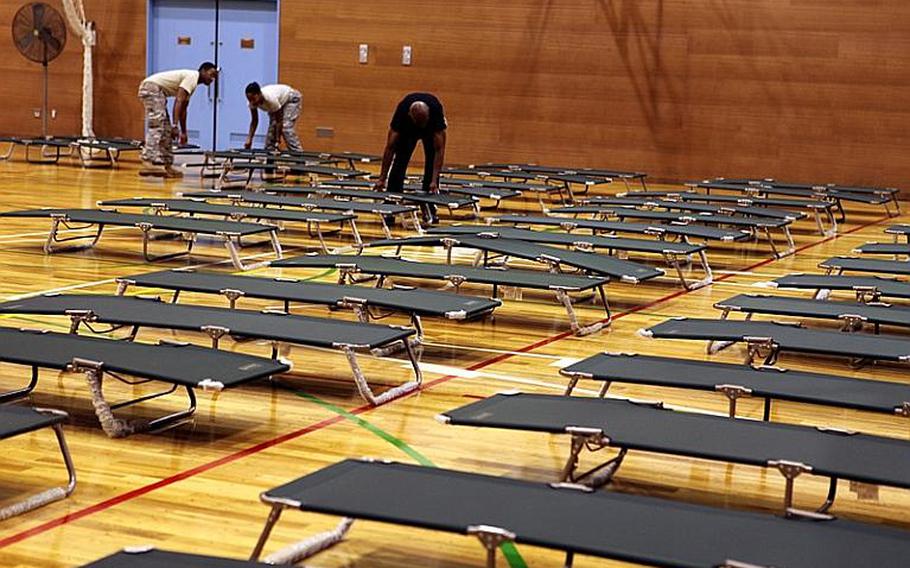 Yokota Air Base personnel at the Samurai Fitness Center begin setting up 400 cots for base residents who had to evacuate their homes due to heavy rain Monday night that led to flooding.