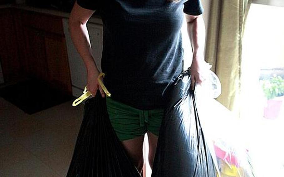 Kendra Weir, a military spouse at Yokota Air Base, carries out trash bags of groceries she cleared out of her refigerator that went bad after heavy rain Monday night led to flooding, power outages and evacuation of some residents from their homes.