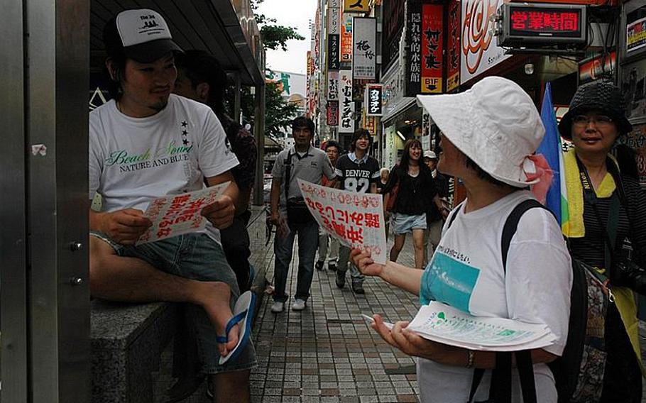 An anti-U.S. military base protester hands out campaign information in Shinjuku Sunday, July 4, 2010, a week before mid-term elections for Japan&#39;s Upper House. The vote will be Naoto Kan?s first litmus test after taking over the helm from Yukio Hatoyama, who resigned in early June after failing to fulfill a promise to renegotiate plans to move Marine Corps Air Station Futenma on Okinawa.