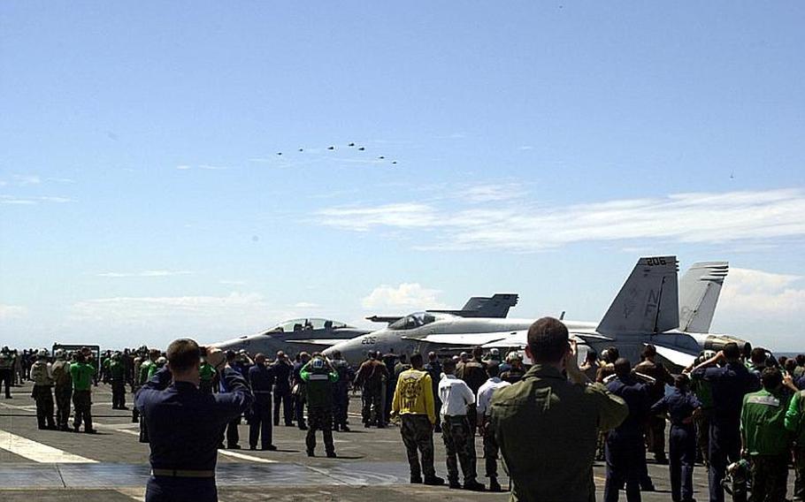 Hundreds of crewmen gather on the deck of the USS George Washington on Monday to watch and photograph one of four waves of aircraft that passed during a flyover, part of the Invincible Spirit joint military exercise being staged off the east coast of the Korean peninsula by the U.S. and South Korea.
