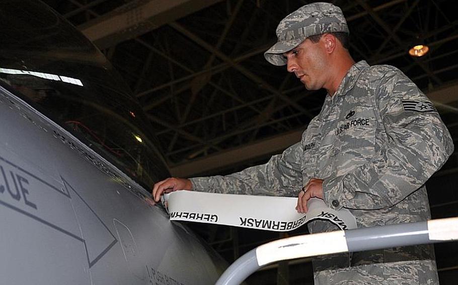 Staff Sgt. Robert Randolph, of the 35th Air Maintenance Squadron at Misawa Air Base, Japan, peels off the backing of a sticker to display the name of the 35th Fighter Wing's newest commander stenciled on an F-16 fighter. Col. Michael Rothstein took command of the wing during the ceremony.