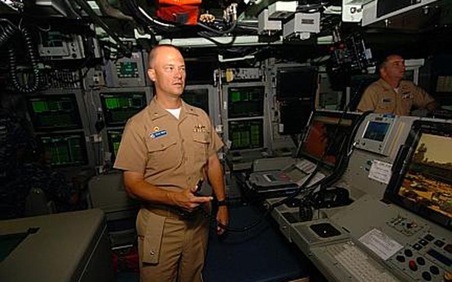 Instead of a periscope, USS Hawaii commanding officer Cmdr. Stephen Mack uses a controller to move a photonics mast that takes digital images of the ship's surroundings at Yokosuka Naval Base, Japan, on Tuesday. The images are then sent to a large-screen high-definition television. The visit by the Hawaii is the first by a Virginia class submarine to the 7th Fleet's Western Pacific-based area of operations.
