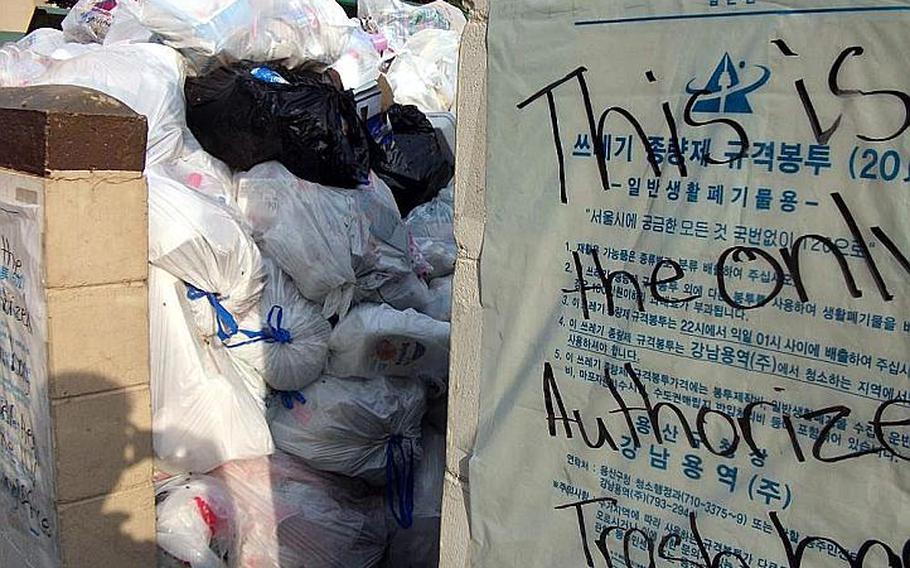 A South Korean-authorized biodegradable garbage bag with the message ''This is the only authorized trash bag'' is taped to the side of a garbage disposal site at Hannam Village. Piles of improperly sorted trash in unmarked garbage bags were picked up by U.S. Army Garrison-Yongsan's Directorate of Public Works after South Korean garbage collectors refused to do so.