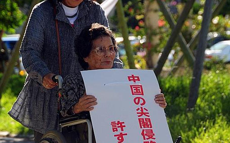 "Do not allow Chinese invasion of Senkaku Islands," reads this sign carried by these two Okinawans who attended a rally supportive of the U.S.-Japan Security Treaty Monday in Naha. The Senkaku Islands, located between Okinawa and Taiwan, is administered by Japan but also claimed by China and Taiwan.