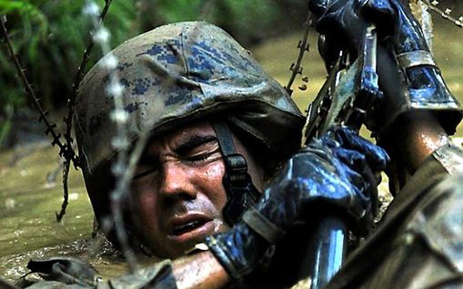 A Marine gets tangled in concertina wire stretched just above the water's surface in a water obstacle on the endurance course. Troops are told to navigate the obstacles on their back and use their rifles to push the wire up and then swim underneath.