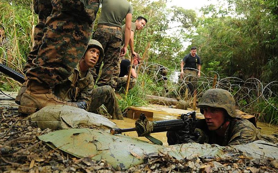 Jungle Warfare Training Center instructors position themselves around the water obstacle and yell directions as troops complete a water obstacle on the endurance course.